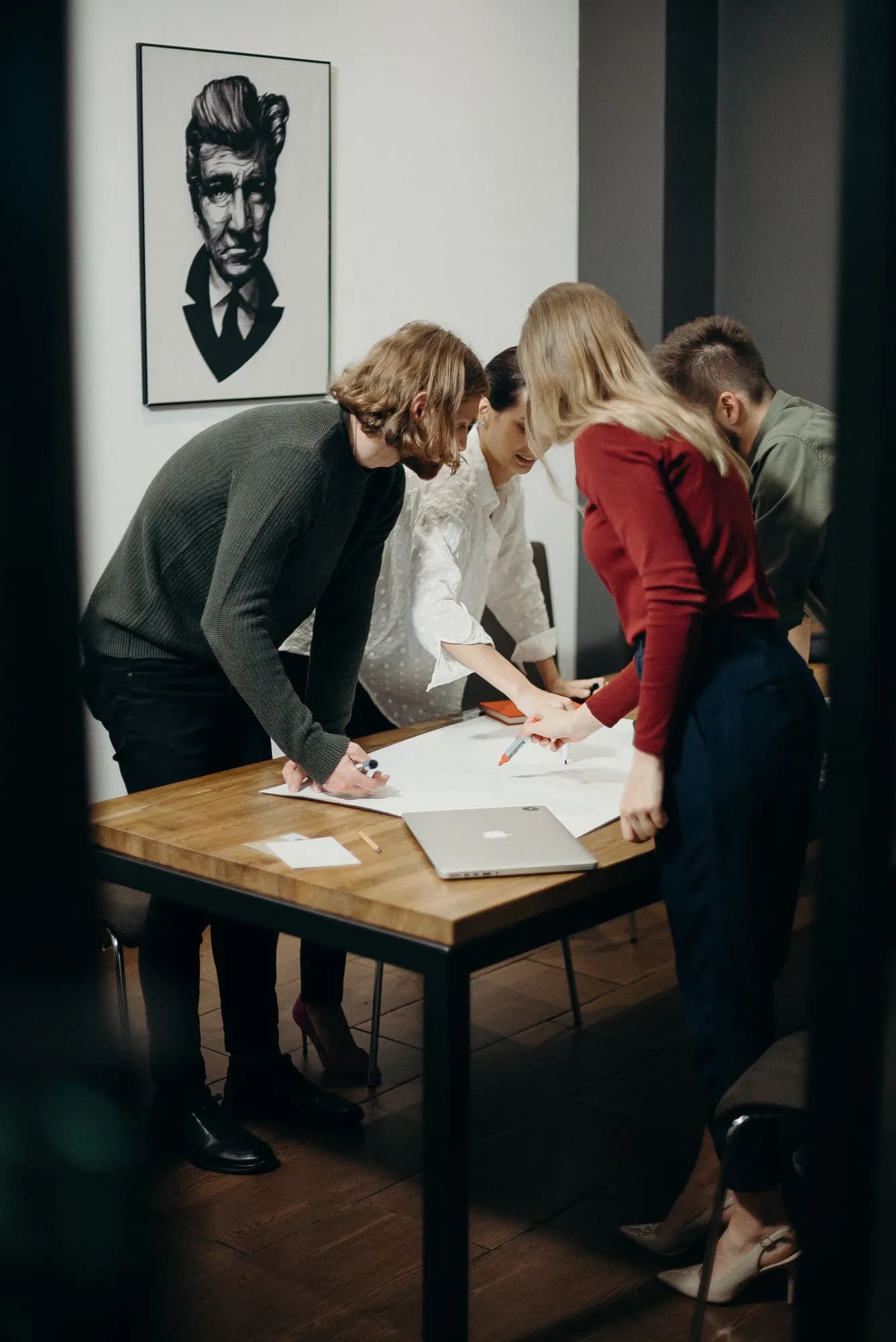 A team collaborates around a table, discussing ideas and sketching on paper.