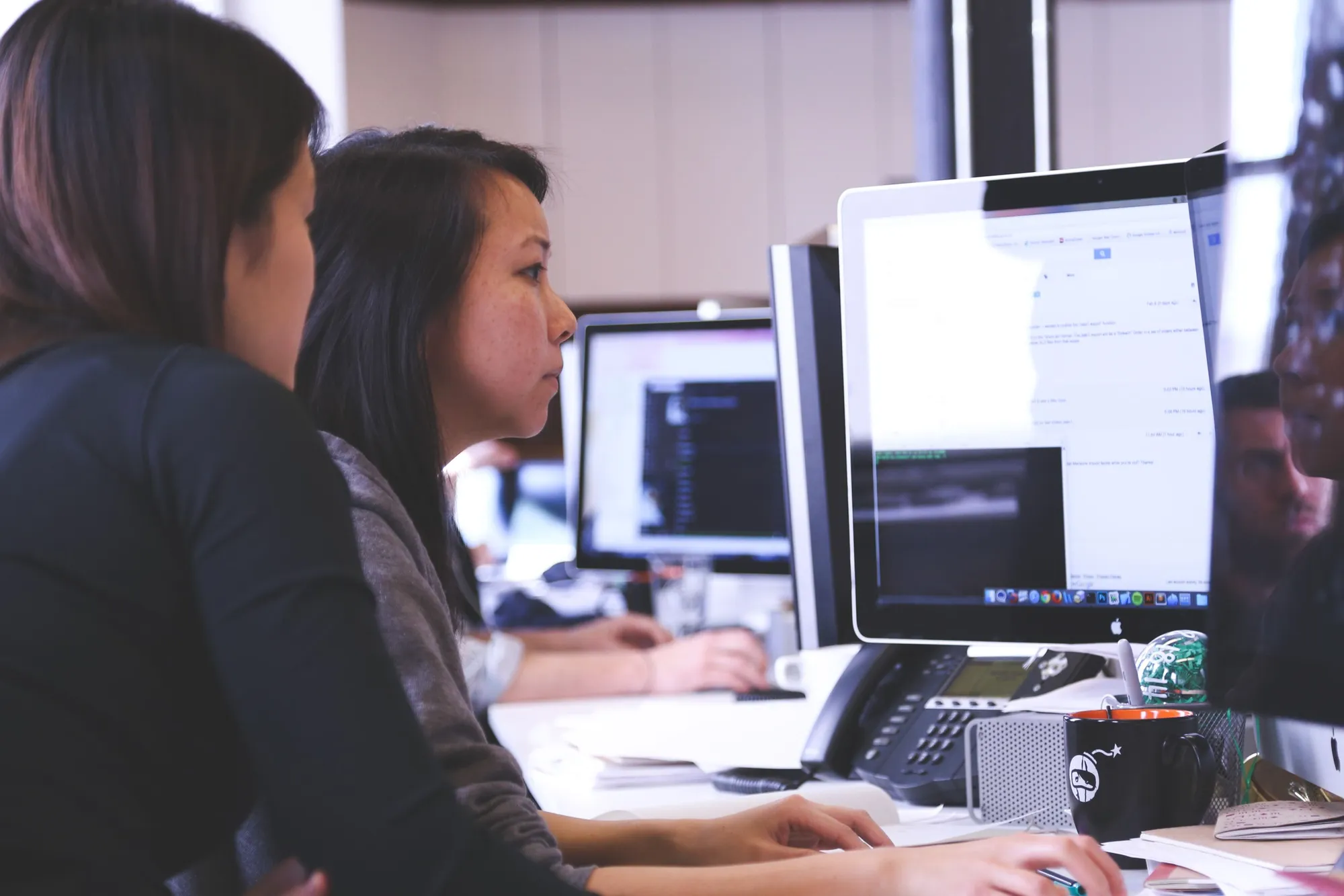 Software developers working together at desktop computers in an office.